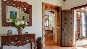 A wooden console table with a mirror, a vase of flowers, and a clock. - Villa Loli - Three Bedroom Villa, Sleeps 6 (Frigiliana)