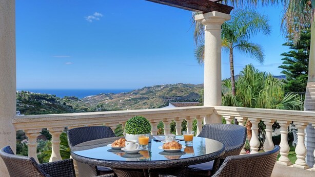 A terrace with wicker furniture, a round table, and a view of the sea and hills. - Villa Loli - Three Bedroom Villa, Sleeps 6 (Frigiliana)