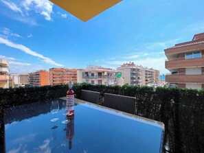 Une terrasse sur le toit avec une table en verre, une bouteille et des verres.