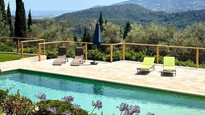 Un espace piscine doté de chaises longues et offrant une vue sur un paysage montagneux.