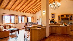 A spacious kitchen with wooden cabinets, a central island, and a dining area with a sofa and chairs.