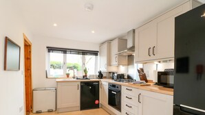 Une cuisine moderne avec des meubles blancs, un lave-vaisselle, une cuisinière et un four à micro-ondes.