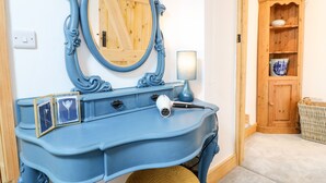 Une coiffeuse bleue avec un miroir, une lampe et un sèche-cheveux.