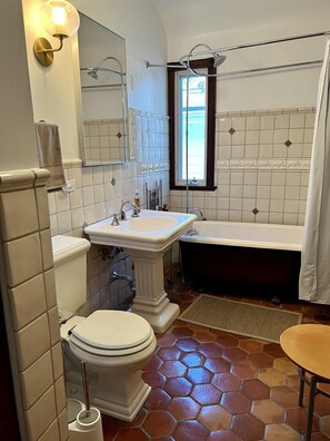 A bathroom with a toilet, sink, bathtub, and a small table. - Historic Oak Park Residence (Oak Park)