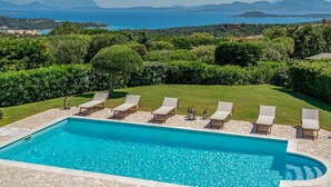 Une piscine rectangulaire à l’eau d’un bleu limpide, entourée de carreaux de pierre.
