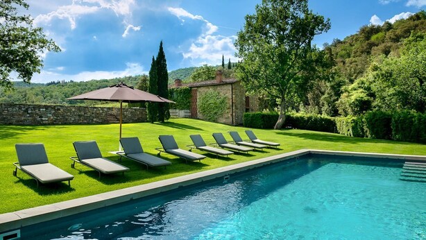 Ein Schwimmbecken mit Liegestühlen und einer Pergola.