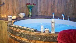 A wooden spa tub with candles, a vase of flowers, and skincare products on the edge. - Villa Vigneto Estate (Gaiole in Chianti)