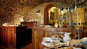 A rustic kitchen with stone walls, wooden cabinets, and a breakfast buffet with various food items and beverages. - Villa Vigneto Estate (Gaiole in Chianti)