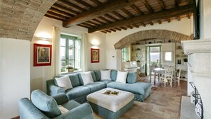 Amplia sala de estar con un sofá modular grande, un pequeño reposapiés y un comedor con mesa y sillas.