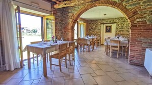 A dining area with stone arches, wooden tables, and chairs.