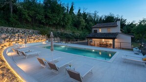 Uma área de piscina com espreguiçadeiras e um muro de pedra.