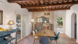 Uma sala de jantar com mesa de madeira, cadeiras, um candelabro e uma lareira de pedra.