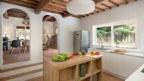 Uma cozinha moderna com uma ilha de madeira, uma geladeira embutida e uma janela com vista para o verde.