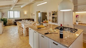 Een moderne keuken met een groot kookeiland, uitgerust met een gasfornuis, oven en koelkast.