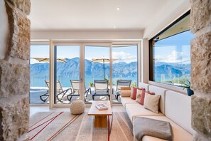 Un salon moderne avec une grande fenêtre, un canapé, une table basse et une vue sur les montagnes.