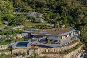 Une villa moderne dotée d’une piscine, de panneaux solaires et d’un mur de soutènement en pierre.