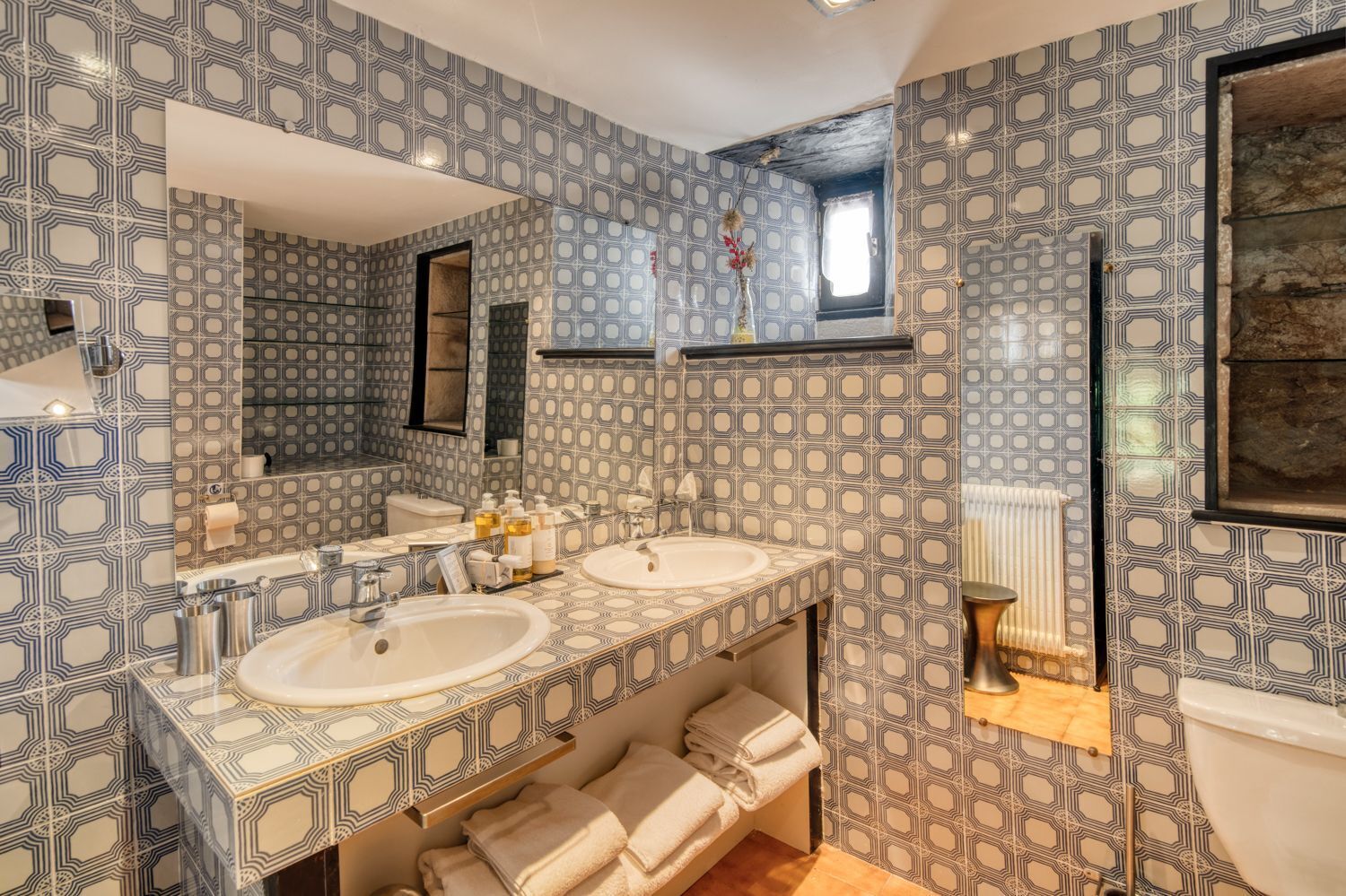 Une salle de bain avec deux lavabos, un grand miroir et des carreaux décorés.