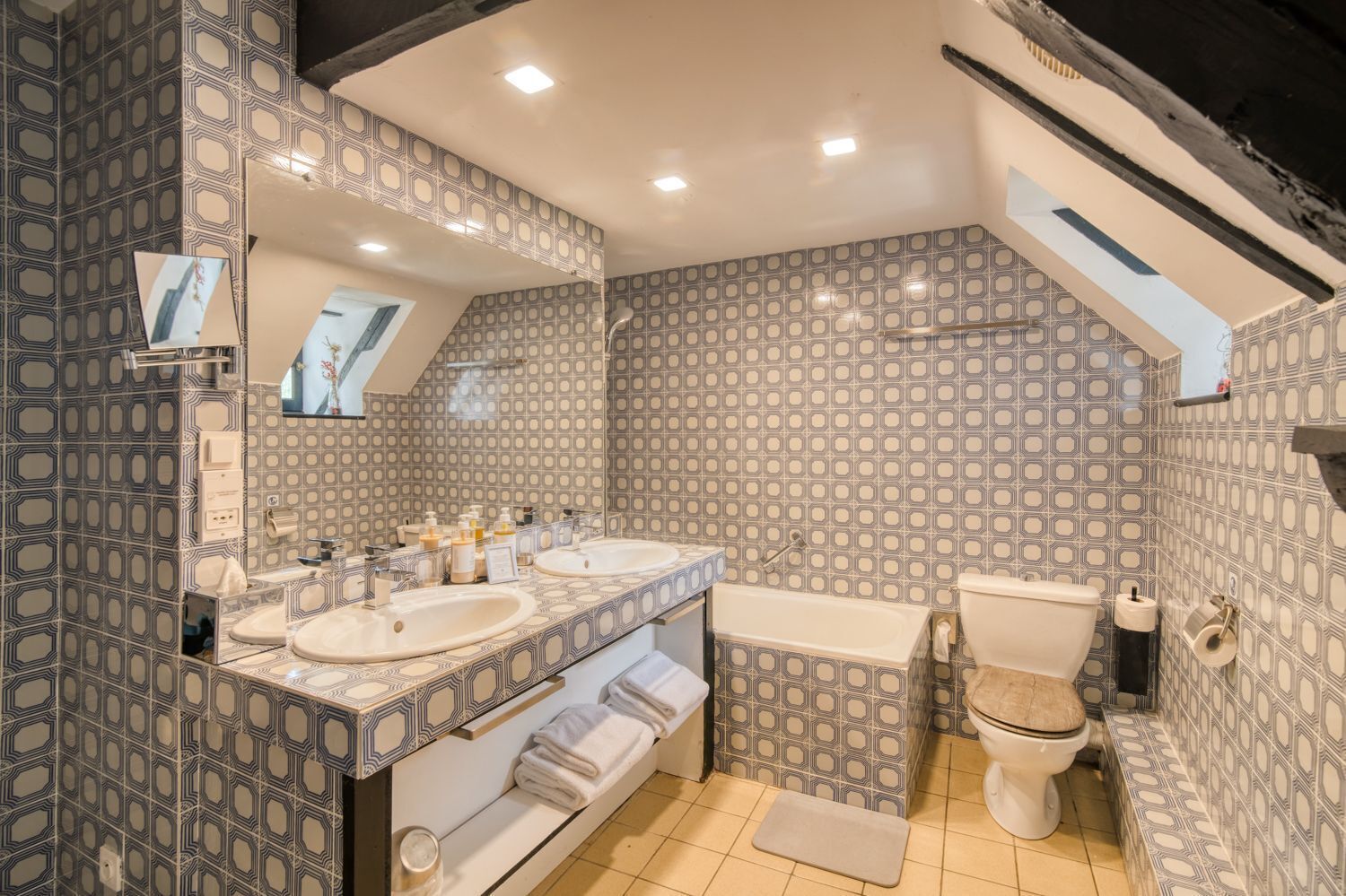 A bathroom with two sinks, a bathtub, and a toilet, all with patterned tiles.