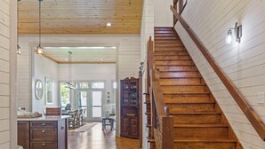 A spacious kitchen with wooden flooring, a dining area, and a staircase with wooden railings.