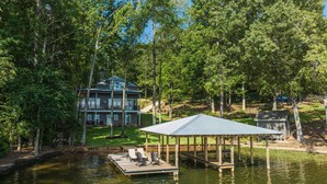 A lakeside property with a large house, dock, and gazebo.
