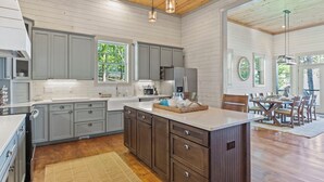 A spacious kitchen with wooden cabinets, a large island, and pendant lighting.