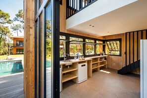 Una cocina moderna con armarios de madera, lavavajillas integrado y grandes ventanales con vistas al exterior.