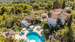 Eine Villa mit Swimmingpool, Sitzgelegenheiten im Freien und Blick auf die umliegende Landschaft.