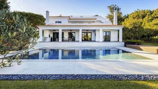 Une maison moderne dotée d’une grande piscine, d’un patio couvert et d’un jardin bien entretenu.