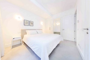 Ein helles Schlafzimmer mit Bett, Nachttisch und Kleiderschrank.