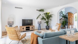 A modern living room with a sofa, armchairs, a TV, and a dining table with glasses. - Villa Mingo - Five Bedroom Villa, Sleeps 10 (Almansil)