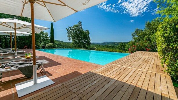 Eine Holzterrasse mit Swimmingpool, Liegestühlen und Sonnenschirmen.
