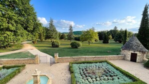 A landscaped garden with a stone fountain, neatly trimmed hedges, and a small stone building. - Domaine Des Maronniers (Carsac-Aillac)