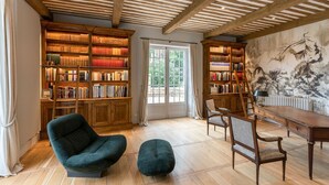 A spacious room with wooden bookshelves, a large window, and a traditional dining table. - Domaine Des Maronniers (Carsac-Aillac)