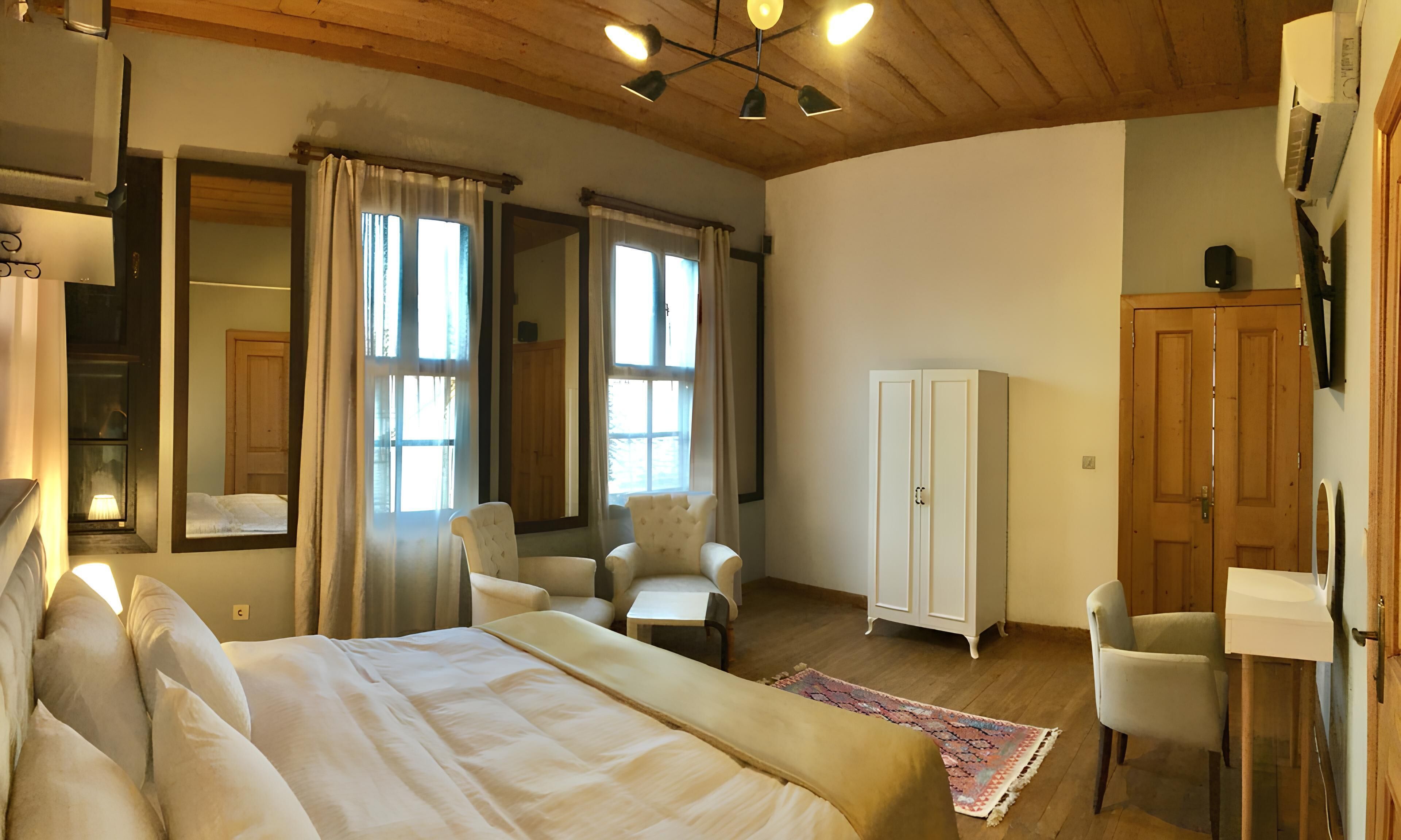 Een slaapkamer met een groot bed, twee stoelen, een kledingkast en een bureau.