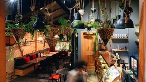 Un restaurante acogedor con vigas de madera, plantas colgantes y una zona de bar.