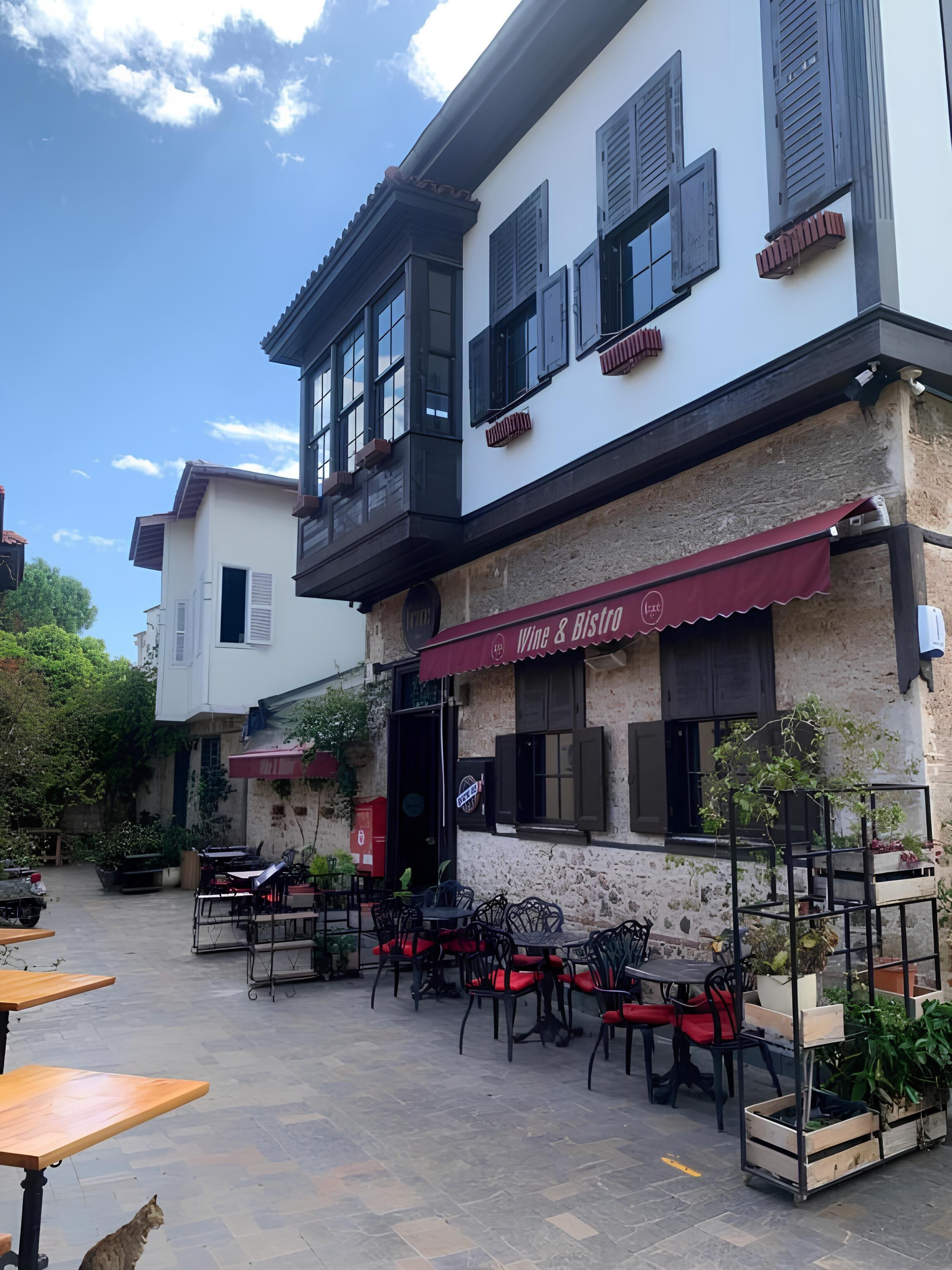 A building with a cafe named "Wine & Risto" featuring outdoor seating and a stone facade.