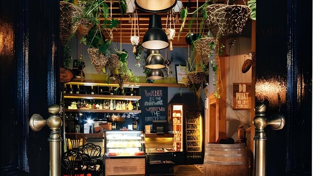 Un interior con plantas colgantes, una zona de bar y un barril de madera.