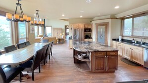 Una cocina amplia con una isla grande, armarios de madera y un comedor con una mesa larga y sillas.
