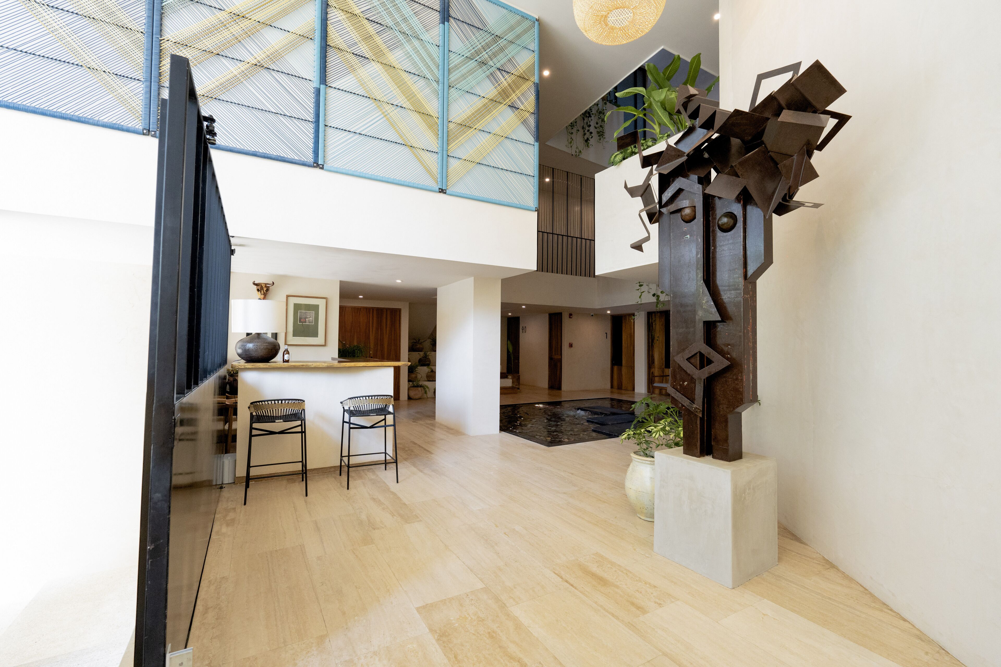 A spacious interior with a modern kitchen, a dining area with bar stools, and a unique metal sculpture.