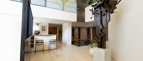 A spacious interior with a modern kitchen, a dining area with bar stools, and a unique metal sculpture.