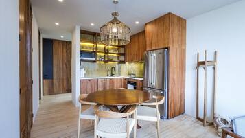 A modern kitchen with wooden cabinets, a stainless steel refrigerator, and a dining table with chairs.