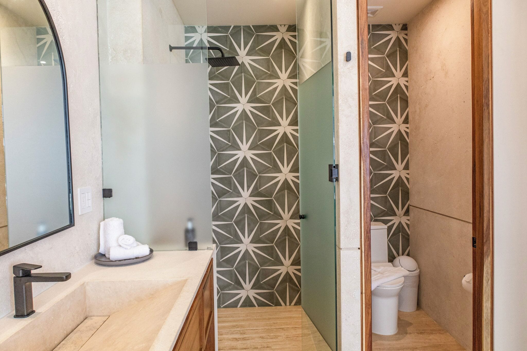 A modern bathroom with a large mirror, a sink, and a shower area.