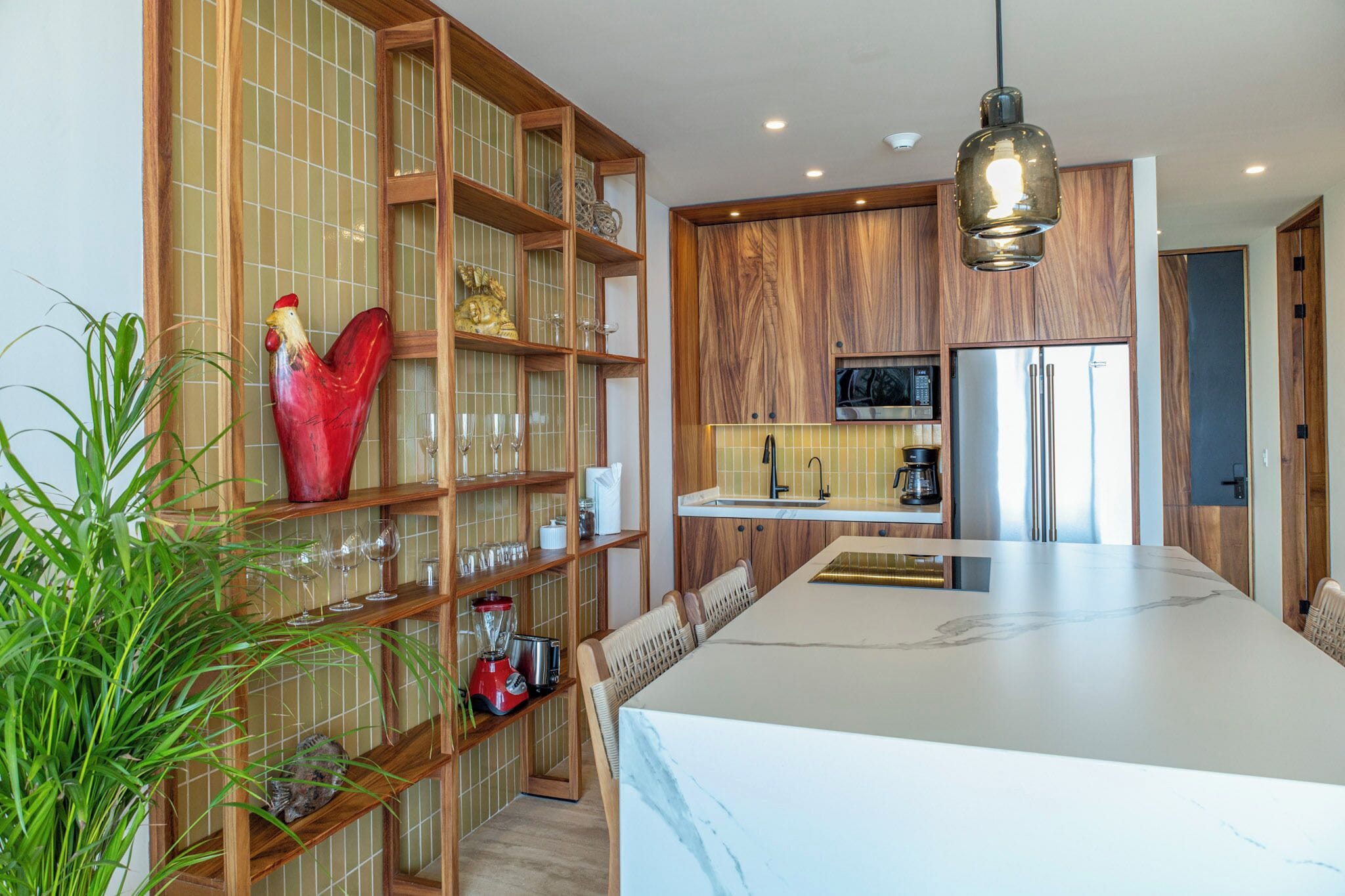 Une cuisine moderne avec un îlot en marbre, des étagères en bois et un décor représentant un coq rouge.