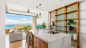 Cozinha moderna com uma ilha grande, armários de madeira e vista para o mar.