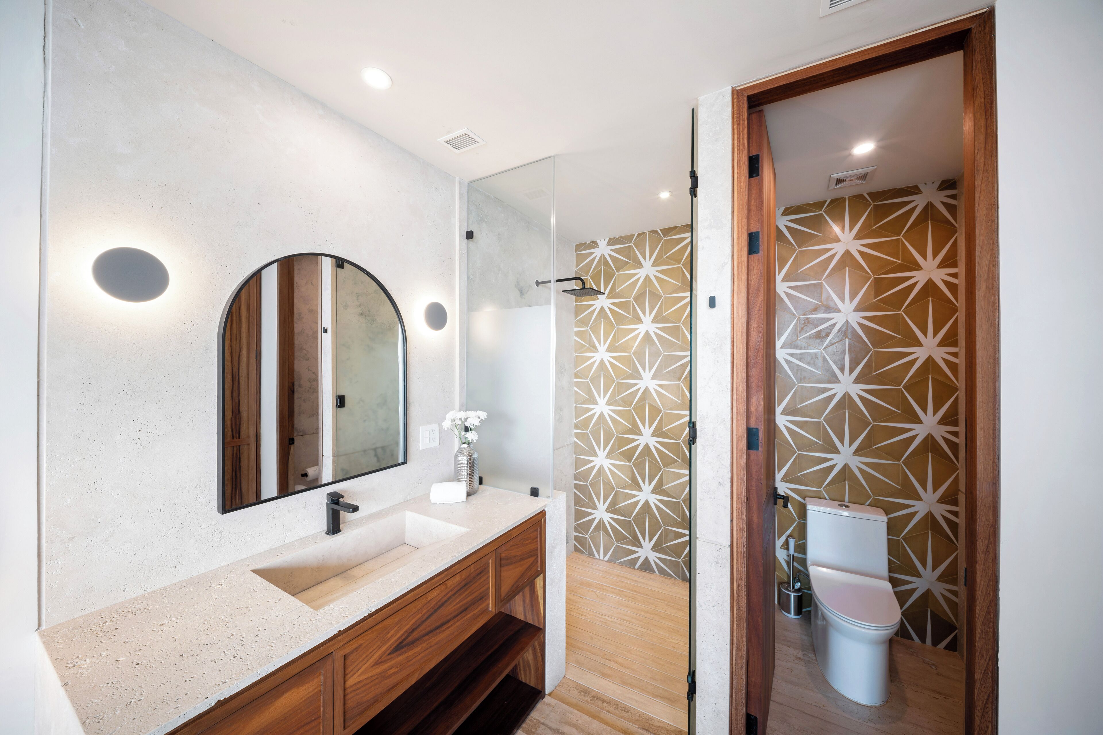 Un baño moderno con un espejo grande, un lavamanos y una zona de ducha.