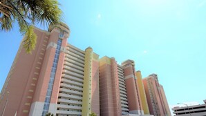A multi-story hotel with a modern design, featuring a series of balconies and a prominent central tower.