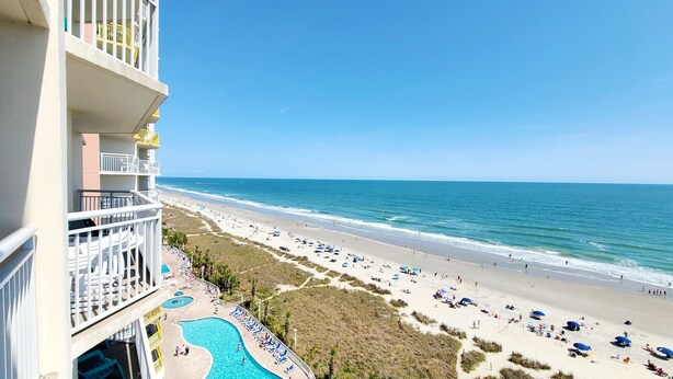 A hotel with a pool, beach, and ocean view.