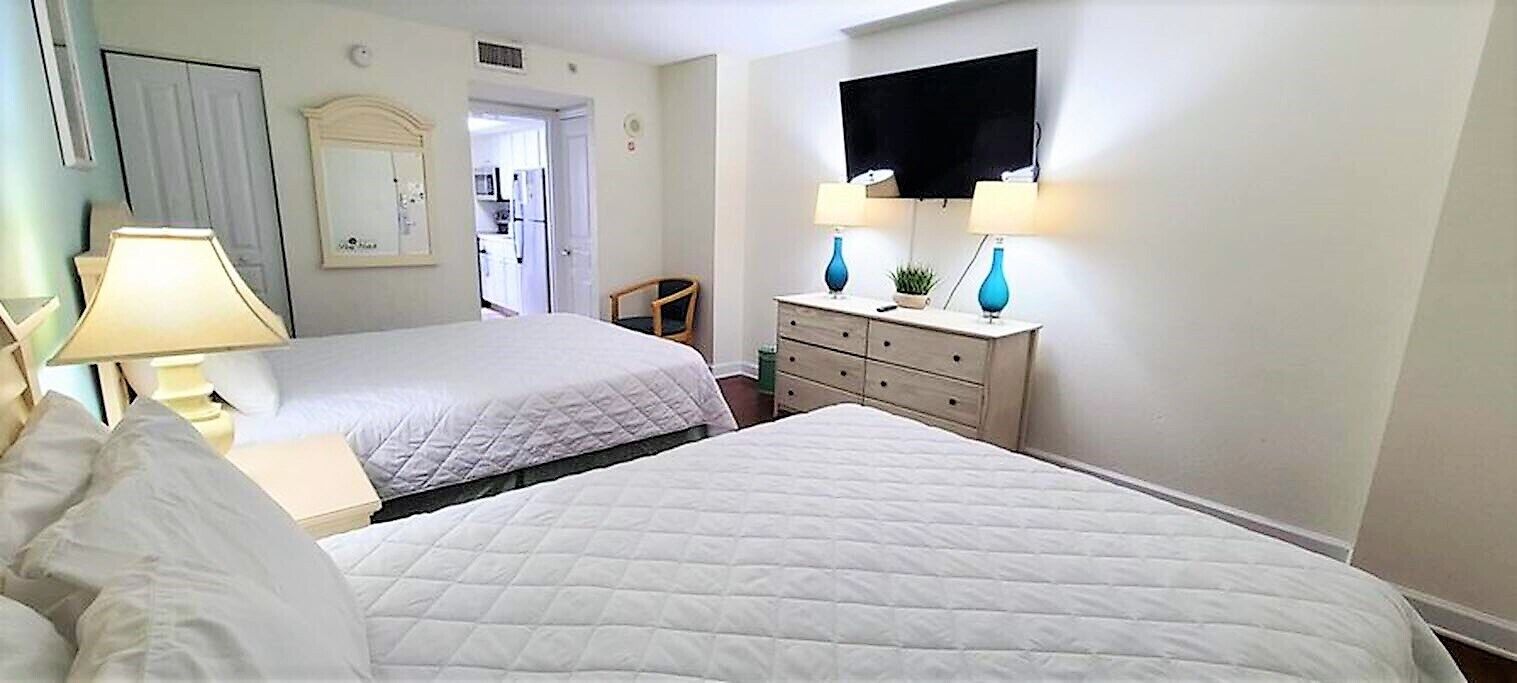 Een hotelkamer met twee bedden, een dressoir, een televisie en een lamp.