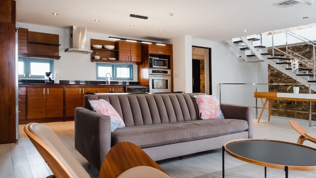 A modern living room with a sofa, wooden chairs, a dining table, and a kitchen in the background. - Casa Azul (Panama City)