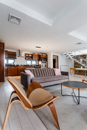 A modern living room with a sofa, wooden chairs, a dining table, and a kitchen in the background. - Casa Azul (Panama City)